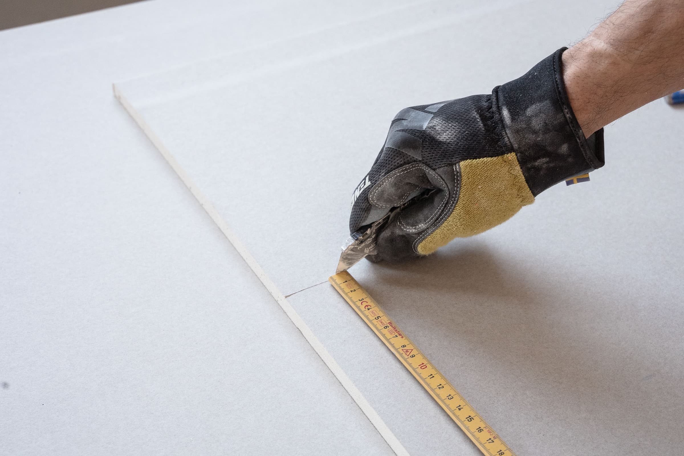 Drywall specialist measuring and cutting wallboard with precision