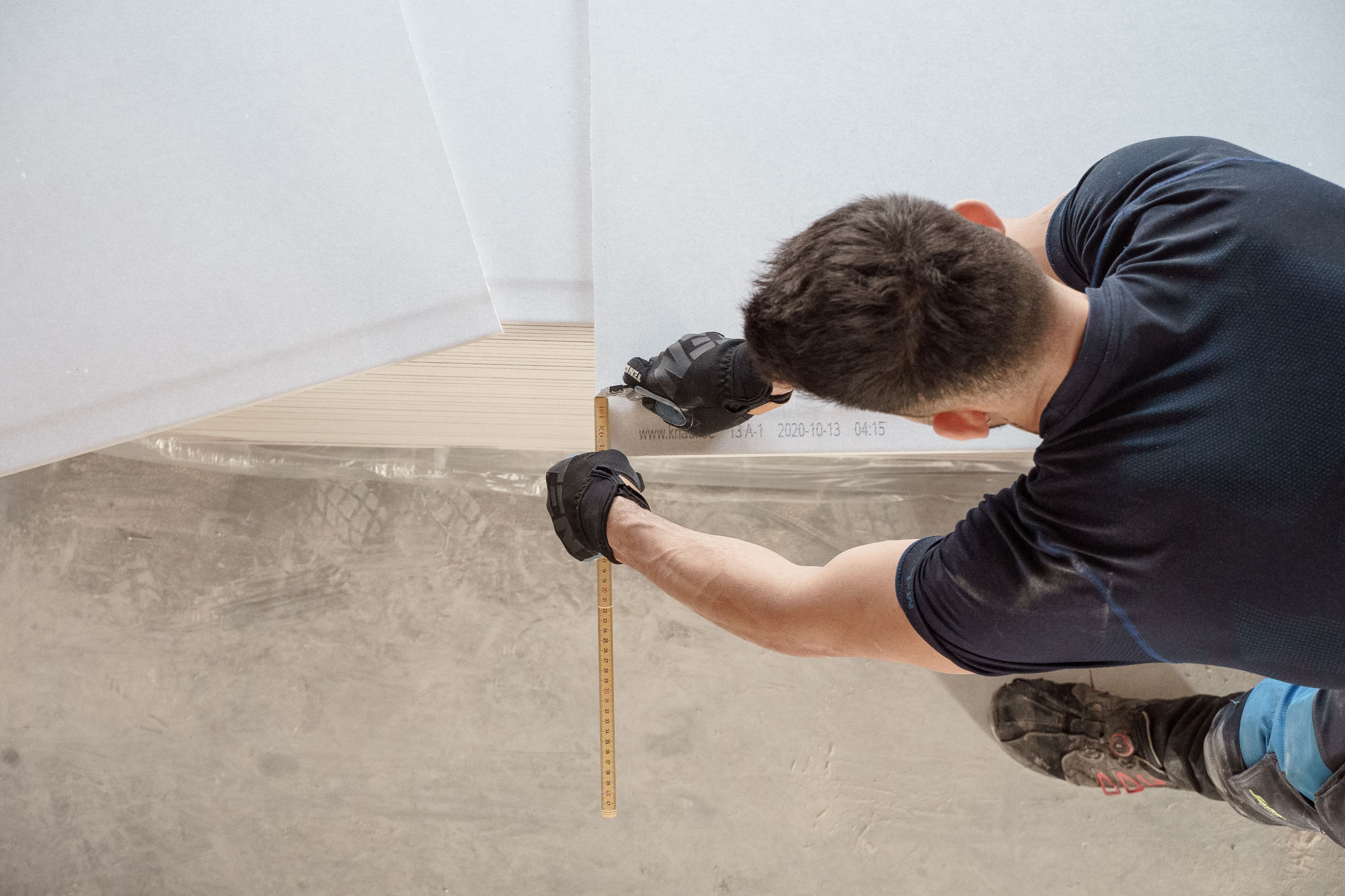 Drywall specialist carefully measuring an interior wall detail